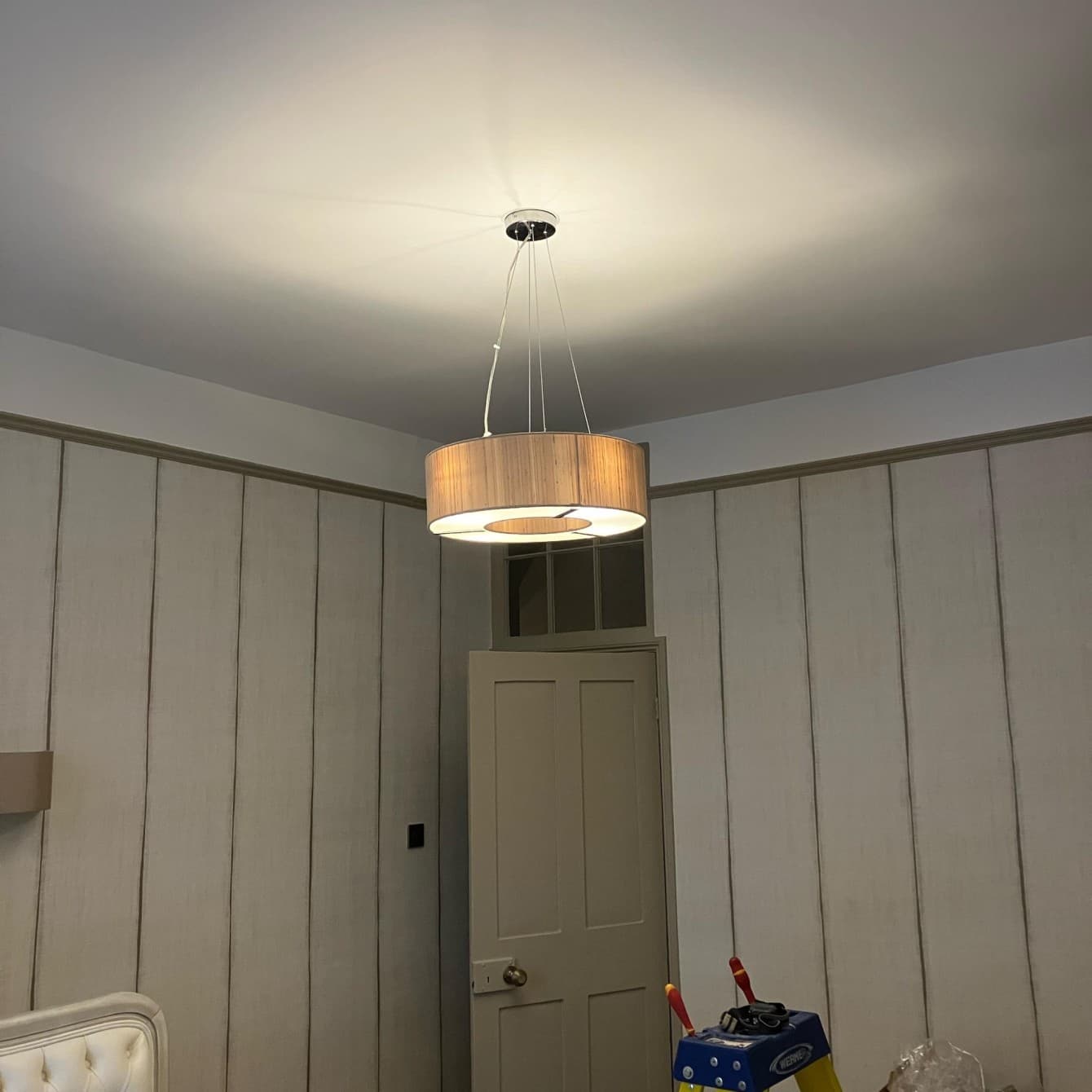 Modern drum pendant light fitted to the ceiling of a panelled bedroom