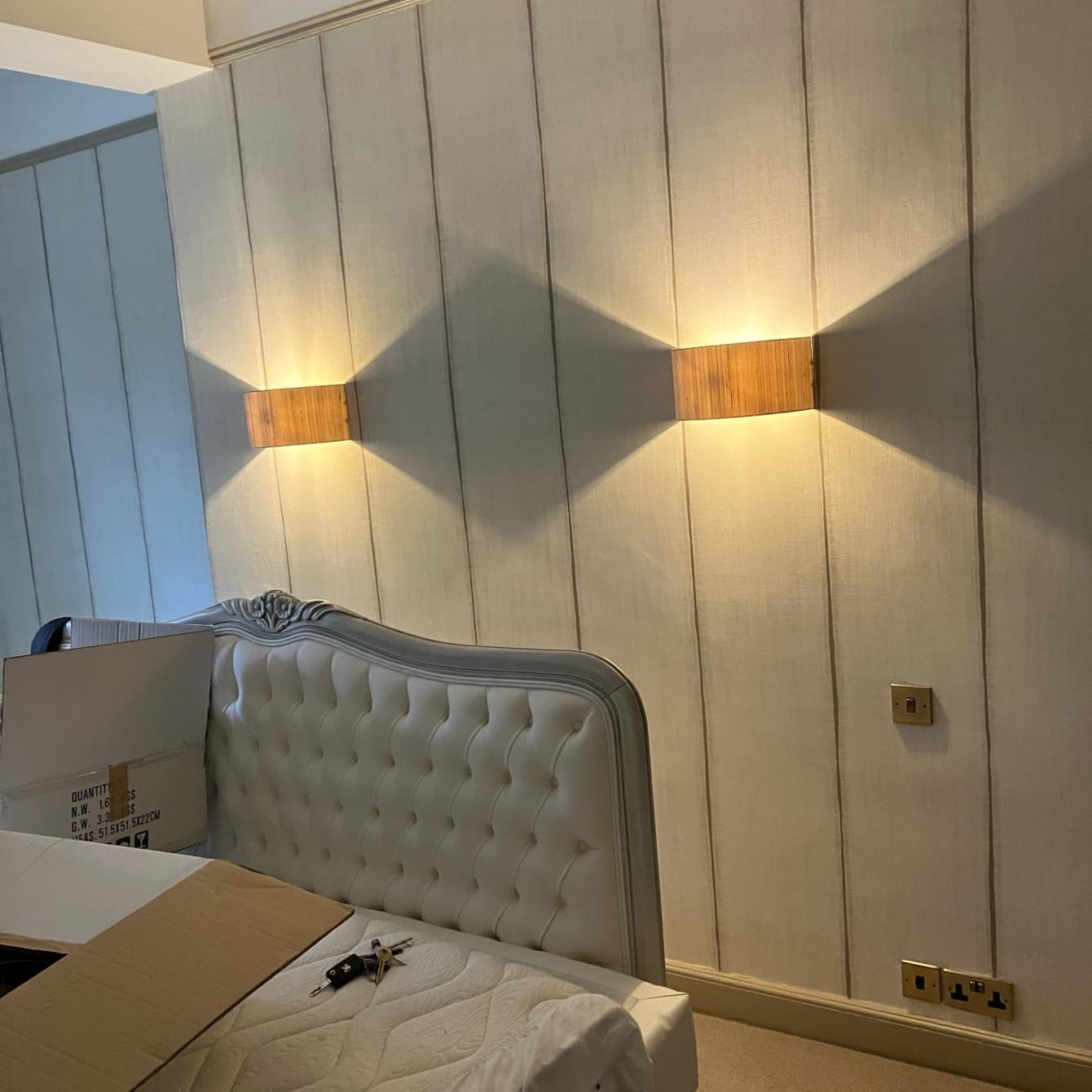 A pair of timber up-and-down wall lights fitted above a bedroom headboard