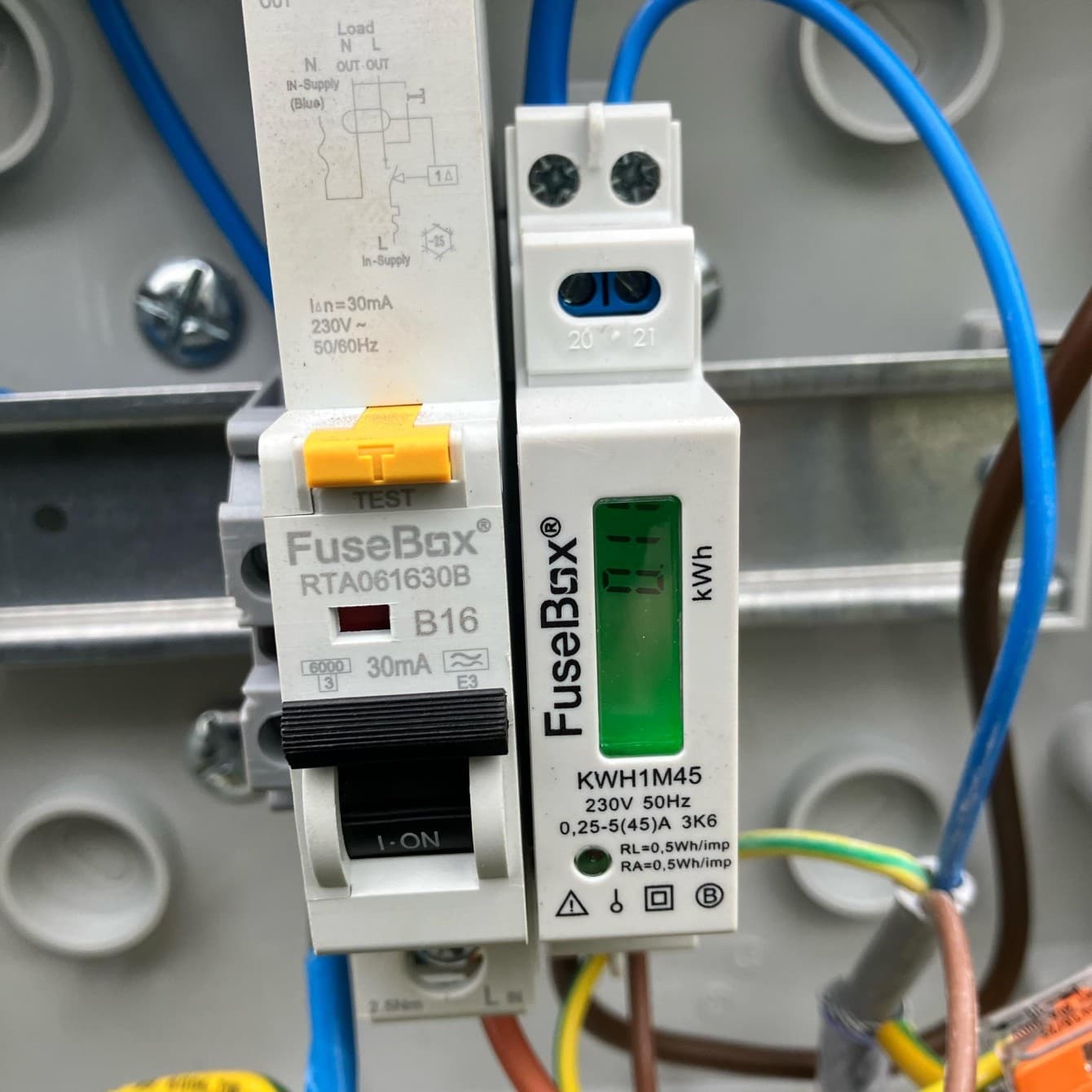 Close-up of a new RCBO and energy meter on the busbar of a fresh board